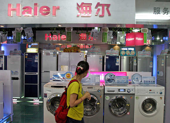 A woman walks past a Haier home appliance store in Shanghai.