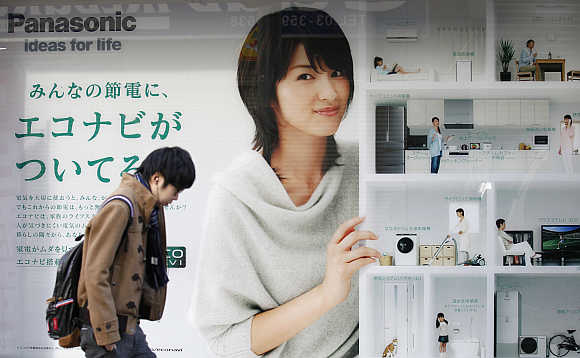 A man walks past an advertisement board of Panasonic outside an electronic shop in Tokyo.