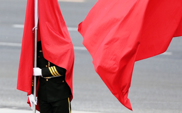 A flag is seen covering the face of an honor guard during a welcoming ceremony for the visiting Greece's Prime Minister Antonis Samaras outside the Great Hall of the People in Beijing.