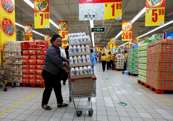 A shopper pushes a cart loaded with beverage bottles at a supermarket in Beijing.