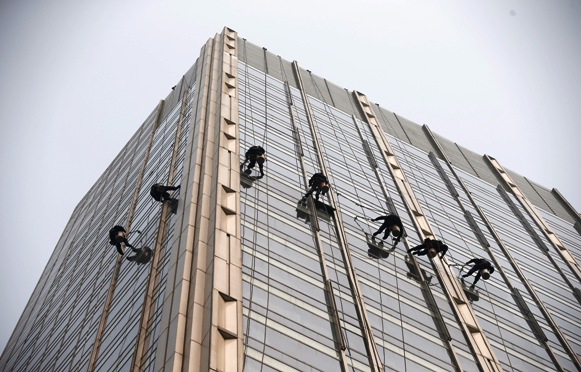 Window cleaners work on a building during hazy conditions in Beijing.