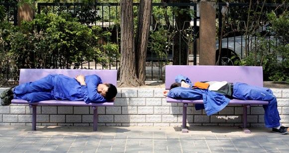 Workers take a nap on a bench in Beijing.
