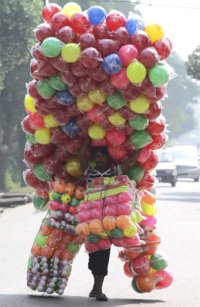 A vendor carries plastic balls for sale as he walks down the streets of Noida.