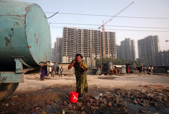 A labourer washes her face from a water tanker in front of residential apartments undergoing construction in Noida on the outskirts of New Delhi.