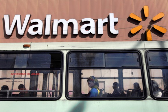A clown sits inside a bus seen in front of a Wal-Mart store in Mexico City.