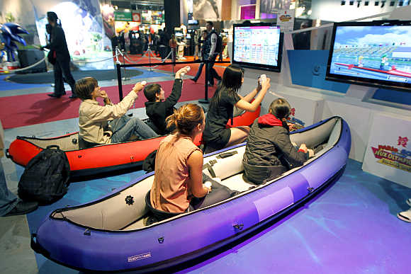 Visitors play a rowing race with Nintendo Wii games during a visit at the Paris Games Week show.