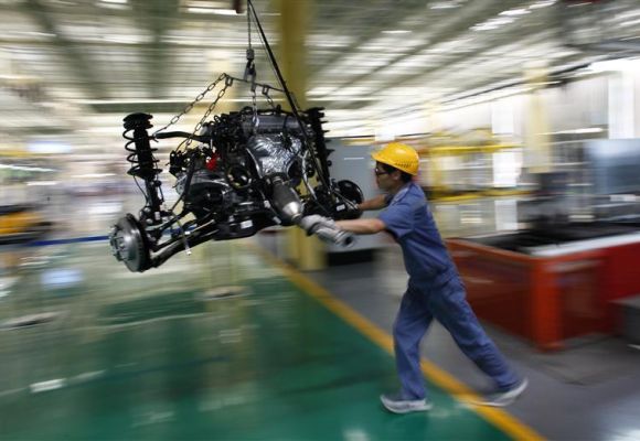 An employee pushes a car engine at a Geely Automobile assembly line in China.