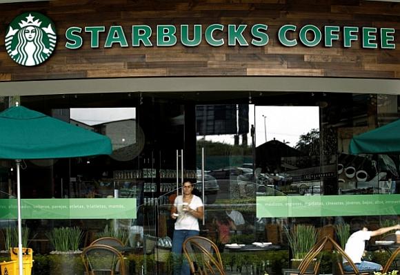 A customer with a cup of coffee leaves the new Starbucks store.