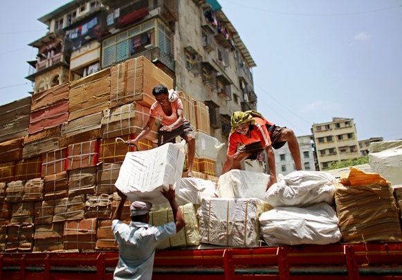 Workers of a transport company load packages on a truck at a wholesale market in Mumbai.