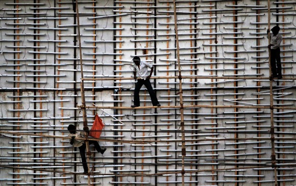 Workers install bamboo poles on a billboard under construction along a road on the outskirts of Ahmedabad.