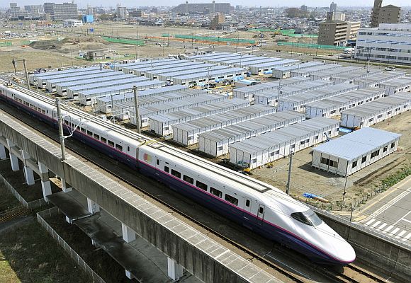 The Shinkansen, or bullet train, is seen speeding past temporary houses.