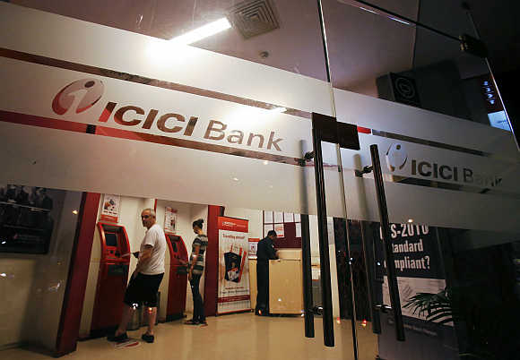 Customers use ATM machines at an ICICI Bank branch in Mumbai.