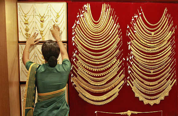 A saleswoman arranges a gold necklace inside a jewellery showroom in Kochi.
