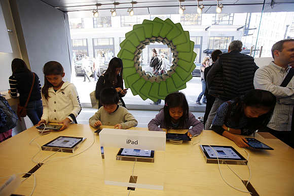 Young holiday shoppers interact with iPads at an Apple Store in San Francisco, California.