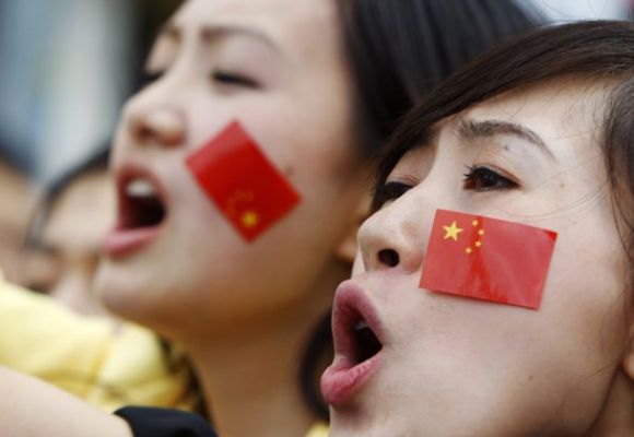 Members of the Chinese community with stickers of the Chinese flag stuck on their faces.