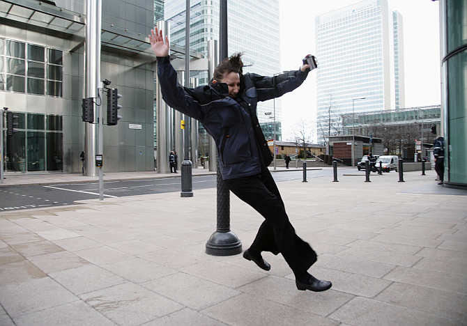 A woman is blown off her feet by the wind in Canary Wharf, London's financial district, United Kingdom.