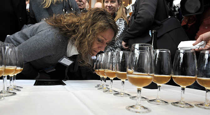 A woman smells samples of champagne from one of the 168 bottles salvaged from a 200-year-old shipwreck near the waters of Aland Islands after it was opened in Mariehamn, Finland.