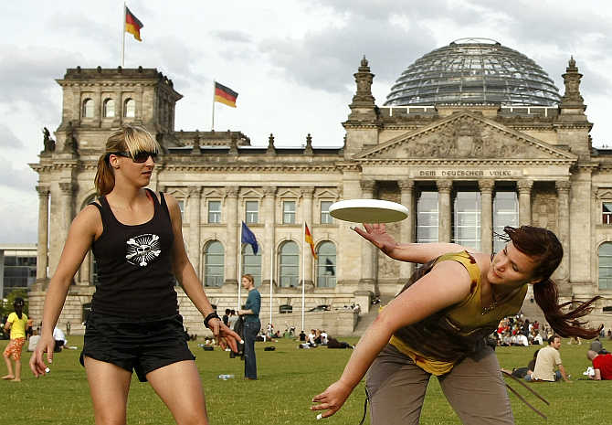 Women play with a frisbee in front of the Reichstag building in Berlin, Germany.