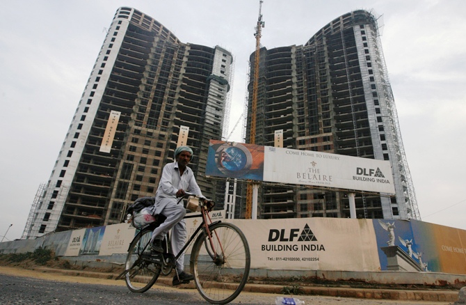 A file photograph shows a man cycles past the construction site of a residential apartment building by Indian property developer DLF Ltd. in Gurgaon.