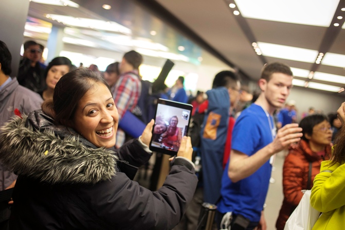 Shirly Tishler of Israel uses an iPad mini to speak to her family back home as she awaits in line to purchase the new Apple iPhone 5S phone at the Apple Retail Store on Fifth Avenue in Manhattan, New York September 20, 2013.