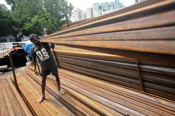A worker loads iron rods in a truck at an iron and steel market in an industrial area in Mumbai September 11, 2013.