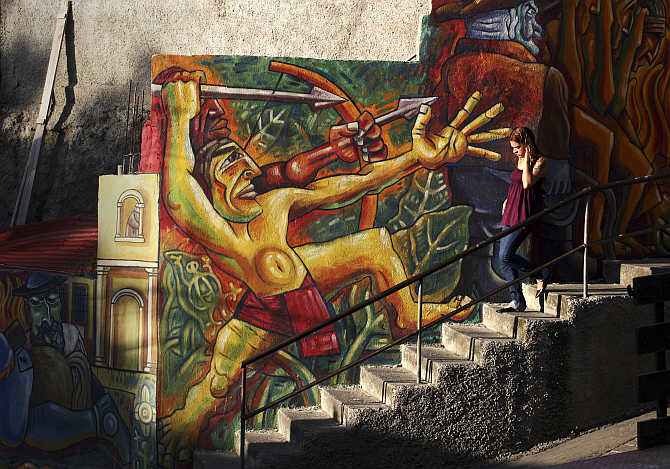 A girl walks past a mural in the neighbourhood of La Pastora in Caracas, Venezuela.