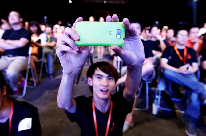 A user of Xiaomi uses his mobile phone to take a photo at a launch ceremony of Xiaomi Phone 2 in Beijing.