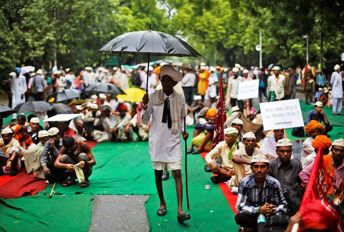 A farmer holds an umbrella as it rains during a day-long protest in New Delhi August 8, 2013.