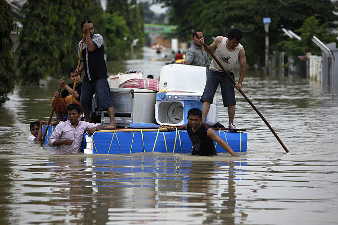 Residents carry their belongings on a makeshift raft at a housing area in Karawang, Indonesia's West java province, after floods caused Citarum River to overflow.