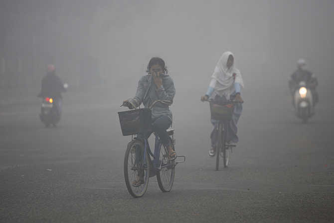Residents cycle through the haze-blanketed town of Sampit, in Indonesia's Central Kalimantan province.