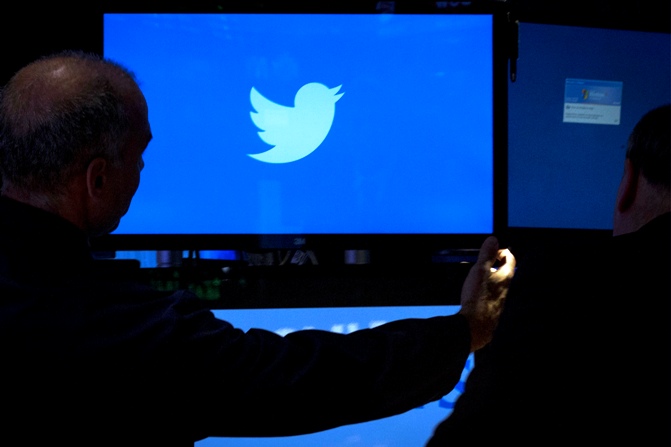An employee adjusts a screen that displays the Twitter logo ahead of the company's IPO on the floor of the New York Stock Exchange.