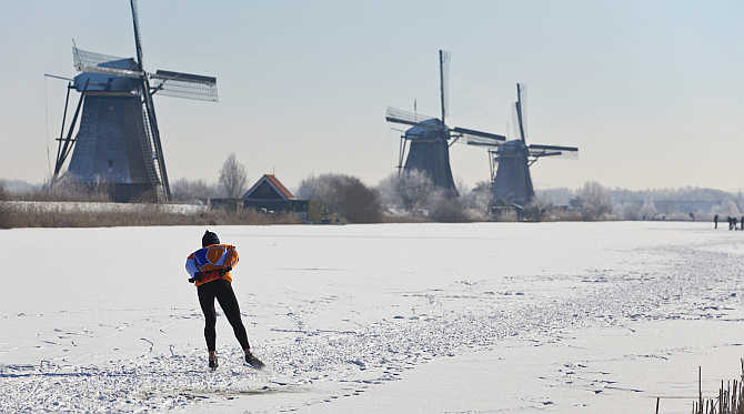 A lone skater skates past three windmills in Kinderdijk near Rotterdam, the Netherlands.