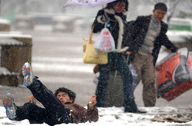 A man falls on a slippery road while on his way to the South Railway Station in Ningbo in east China's Zhejiang province.