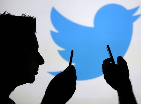 Men are silhouetted against a video screen with a Twitter logo.