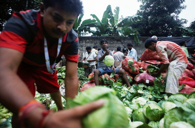 Vendors sort out cabbages along a road outside a wholesale vegetable market at dawn in Mumbai.