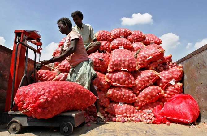 A man weighs a sack of onions before unloading it from a supply truck at a wholesale market in Chennai.