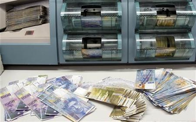 Swiss franc banknotes of several values are sorted in a money counter in a bank in Zurich.