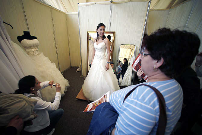 A woman tries on a bridal gown during the E-Marriage Fest wedding fair in Bucharest, Romania.