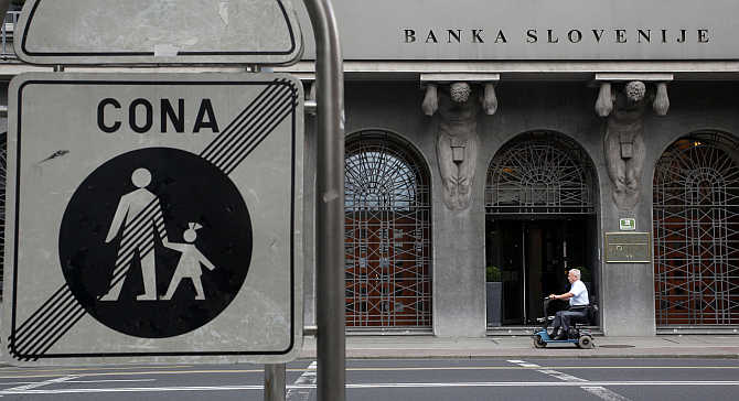 A man in a mobility scooter drives past Slovenia's National Bank in Ljubljana, Slovenia.