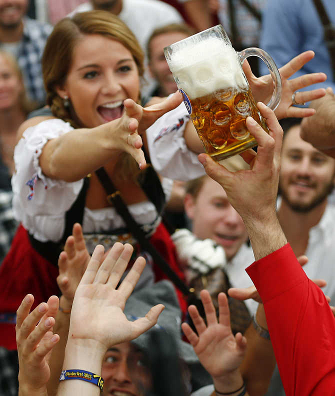 A visitor reaches for one of the first mugs after the opening ceremony of Oktoberfest in Munich, Germany.