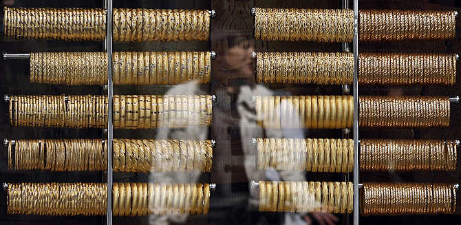 A woman is reflected on a window of a jewellery shop where gold bangles are on display in Istanbul, Turkey.