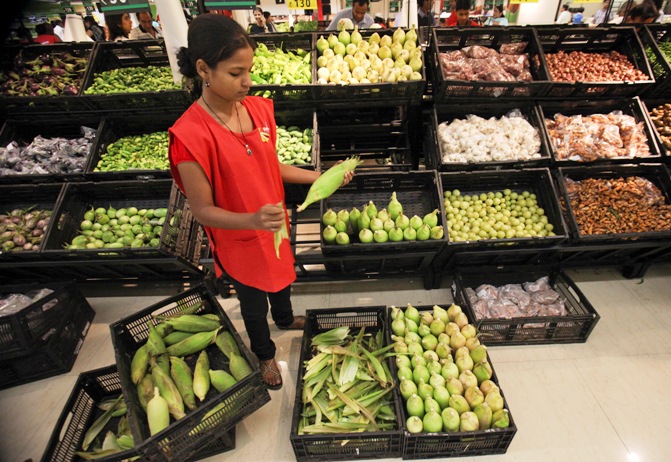 An employee arranges vegetables in the fresh foods section of a Reliance Fresh supermarket in Mumbai.