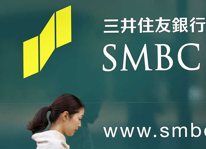 A woman walks past a signboard of Sumitomo Mitsui Banking Corporation in Tokyo.