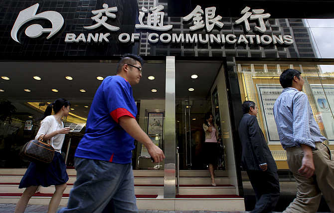 People walk past the Bank of Communications at its central branch in the financial district of Hong Kong.