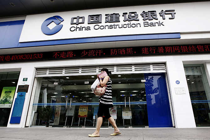 A woman walks past a branch of the China Construction Bank in Shanghai.