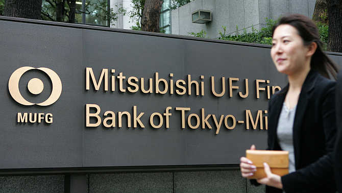 A woman walks past the headquarters of Bank of Tokyo-Mitsubishi UFJ in Tokyo.