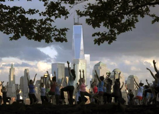 People stretch as they take part in a yoga class across the Hudson River from New York's Lower Manhattan and One World Trade Center in a park in Hoboken, New Jersey