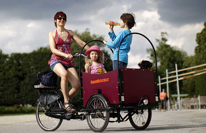 Christine Nouikat and her children Sophia, 4, and Niklas, 9, pose with their transport bicycle in a public park in Vienna, Austria.