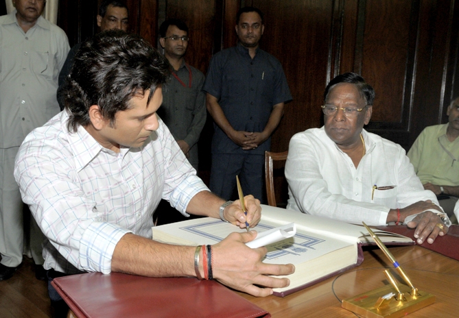 Sachin Tendulkar (L) signs the oath book as India's Minister of State for Parliamentary Affairs V Narayanasamy watches during the swearing-in ceremony at the Indian parliament in New Delhi June 4, 2012.