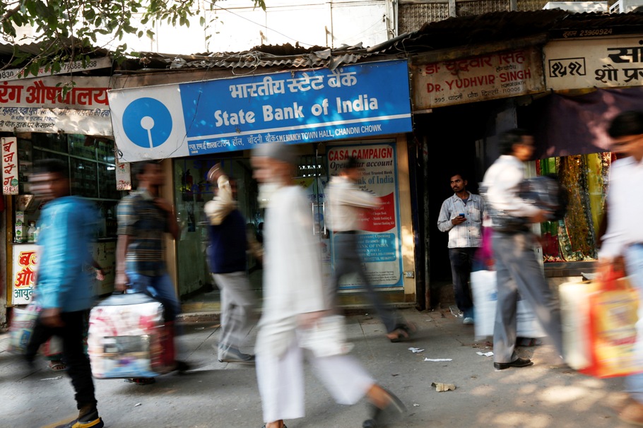 Commuters walk past a State Bank of India branch in the old quarters of Delhi November 13, 2013.